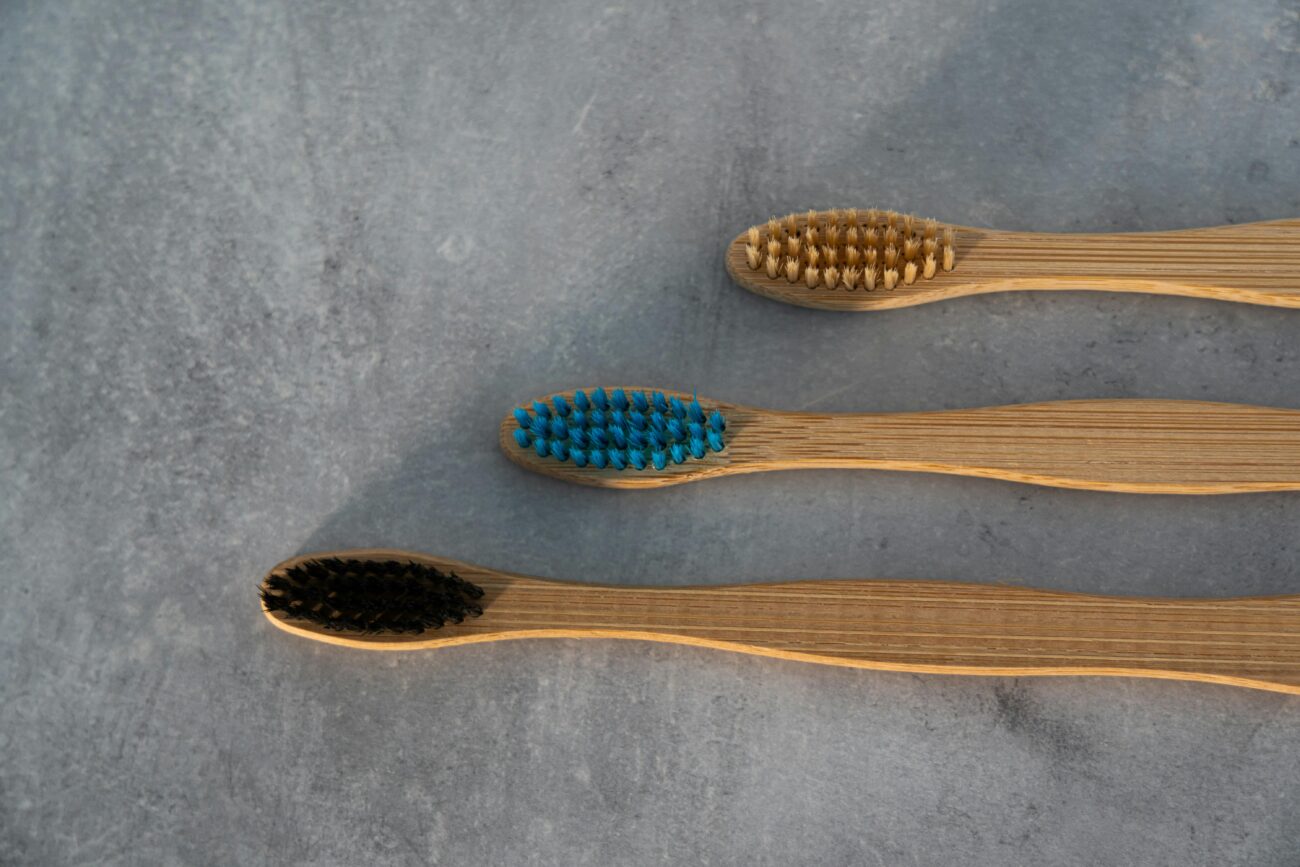 A set of eco-friendly bamboo toothbrushes with colored bristles on a stone background for sustainable living.